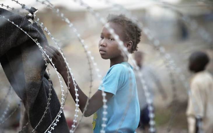 South Sudanese displaced girl behind barbed wire