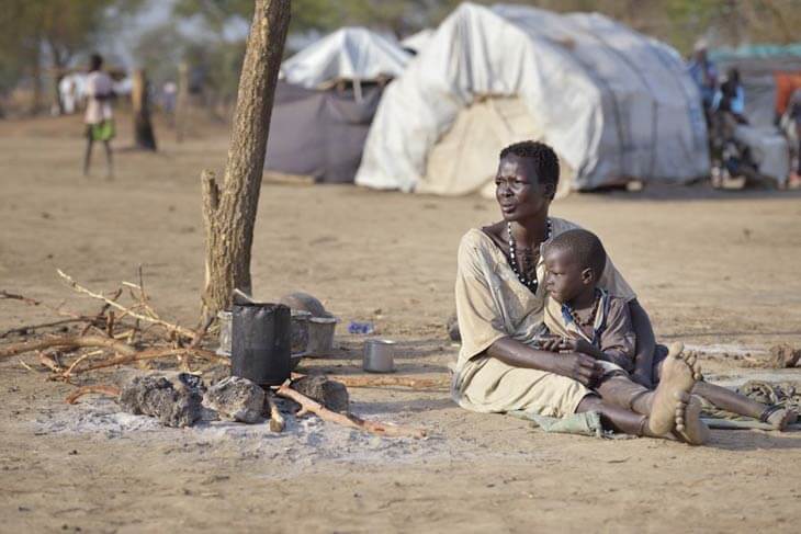 Woman and child sitting on ground in South Sudan camp